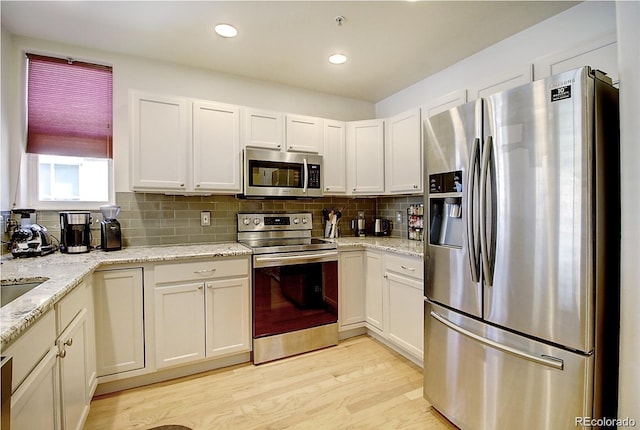 kitchen featuring light wood-style floors, tasteful backsplash, appliances with stainless steel finishes, and white cabinets