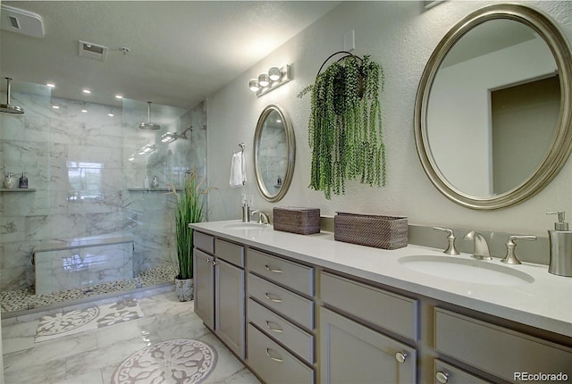 bathroom featuring double vanity, marble finish floor, a marble finish shower, and a sink