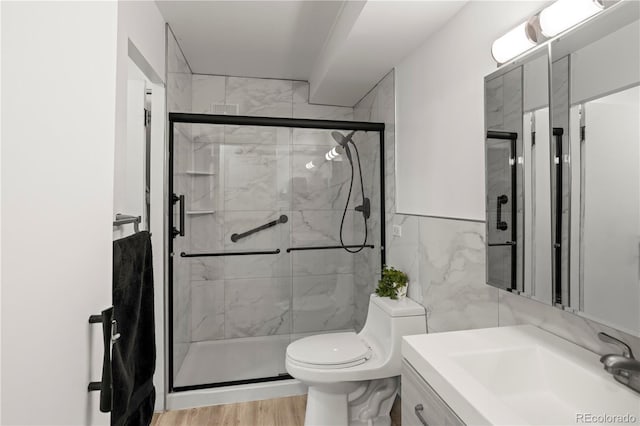 bathroom featuring tile walls, a shower stall, vanity, toilet, and wood finished floors