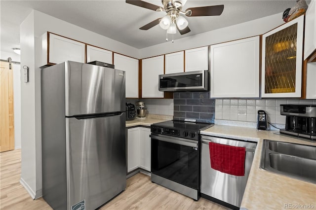 kitchen with stainless steel appliances, light countertops, light wood-type flooring, and decorative backsplash
