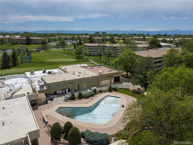 drone / aerial view of a large body of water, a pool area, apartment complex, and a golf club