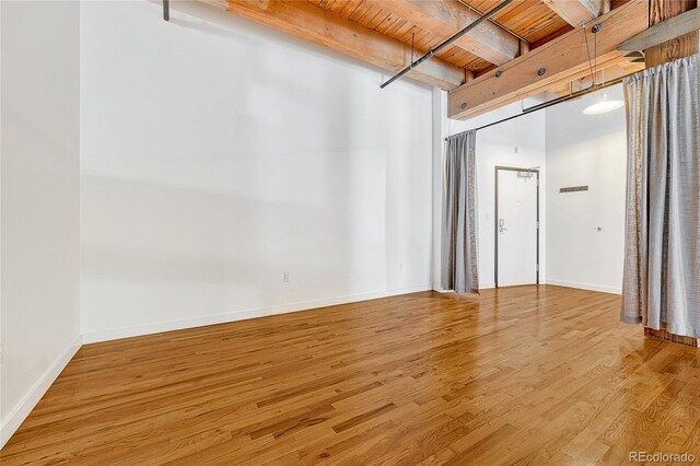 spare room with wooden ceiling, light wood-type flooring, and beam ceiling