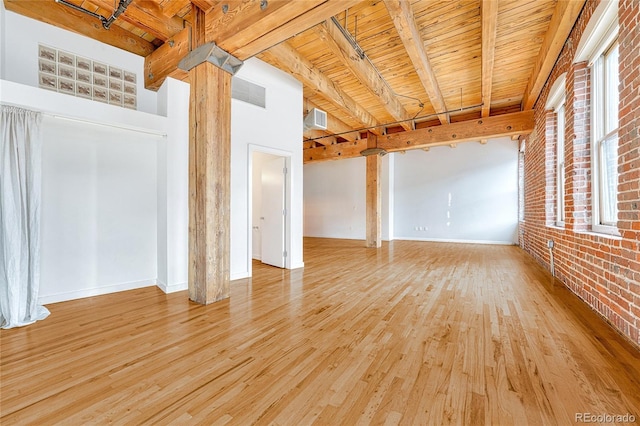 empty room featuring brick wall, light wood-type flooring, beam ceiling, and wooden ceiling