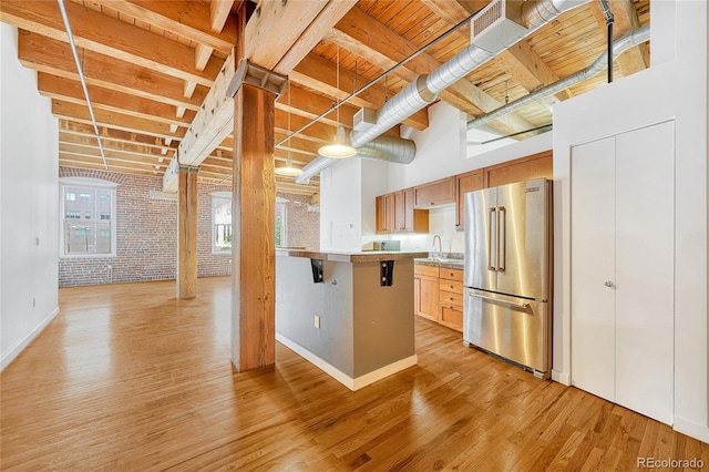 kitchen with brick wall, stainless steel refrigerator, sink, and light hardwood / wood-style floors