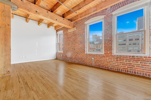 unfurnished room with wood ceiling, a healthy amount of sunlight, light hardwood / wood-style floors, beamed ceiling, and brick wall