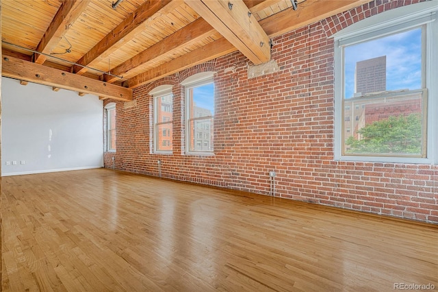 empty room featuring beam ceiling, light hardwood / wood-style flooring, brick wall, and wood ceiling