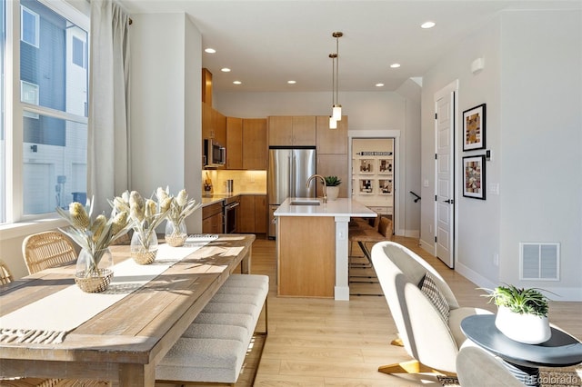 dining space with light wood-type flooring and sink