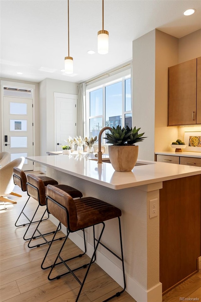 kitchen with a breakfast bar, pendant lighting, and light hardwood / wood-style flooring