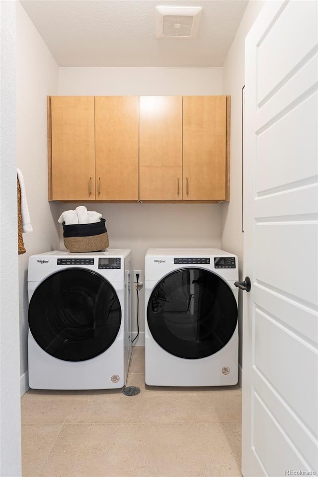 washroom featuring cabinets and washer and clothes dryer