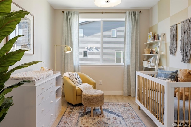 bedroom with multiple windows, light hardwood / wood-style floors, and a nursery area