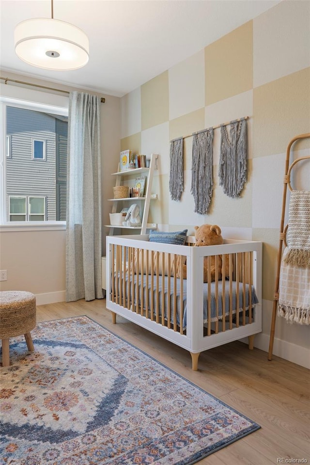 bedroom with hardwood / wood-style floors and a nursery area