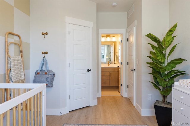 corridor with light hardwood / wood-style floors and sink