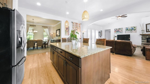10328 Bluffmont Dr, Lone Tree, CO 80124 - kitchen with stainless steel fridge, light wood-style floors, light stone countertops, arched walkways, and pendant lighting