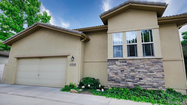 10328 Bluffmont Dr, Lone Tree, CO 80124 - view of front of property featuring a garage, concrete driveway, stone siding, and stucco siding