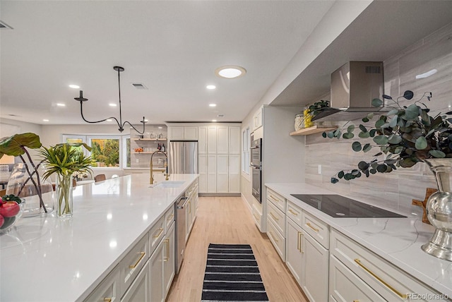 kitchen featuring pendant lighting, sink, black electric cooktop, light wood-type flooring, and wall chimney exhaust hood