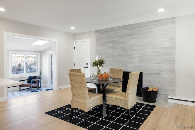 dining area with tile walls, hardwood / wood-style flooring, and a baseboard radiator