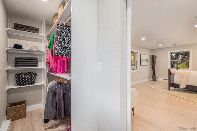 walk in closet with baseboard heating and light hardwood / wood-style floors