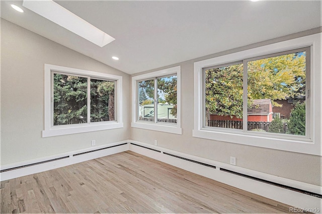 unfurnished room featuring vaulted ceiling with skylight, light wood-type flooring, and a baseboard heating unit