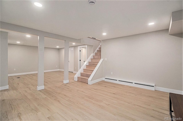 basement featuring baseboard heating and light hardwood / wood-style floors