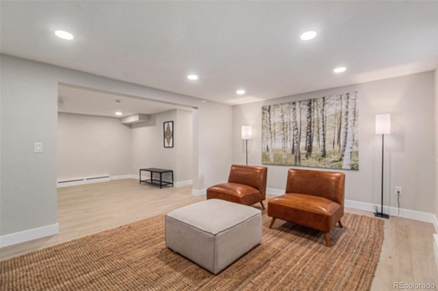 sitting room with a baseboard heating unit and light hardwood / wood-style flooring