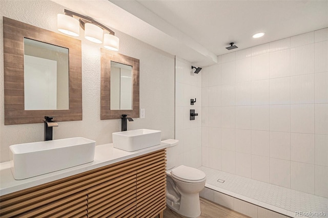 bathroom with vanity, tiled shower, hardwood / wood-style floors, and toilet