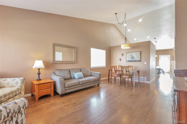 living area featuring recessed lighting, baseboards, high vaulted ceiling, and wood finished floors