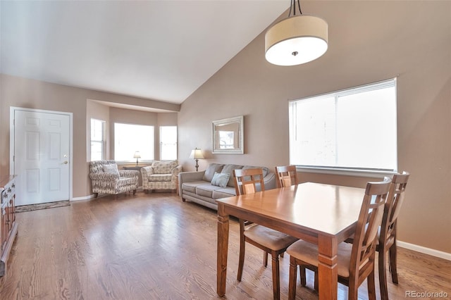 dining area with baseboards, high vaulted ceiling, and wood finished floors