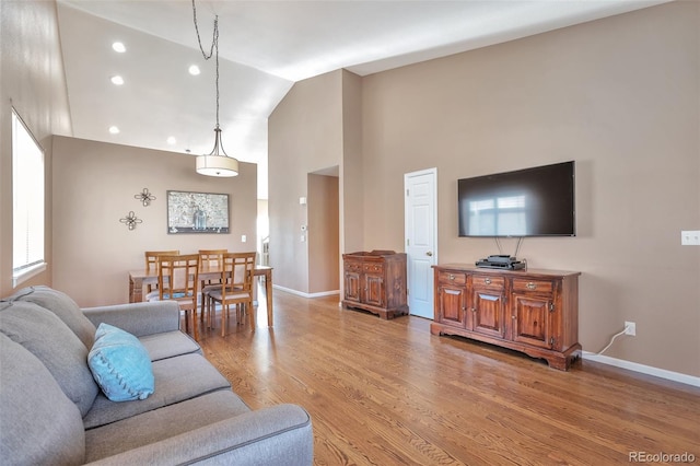 living room featuring recessed lighting, light wood-style floors, baseboards, and high vaulted ceiling