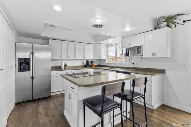 9044 E Nassau Ave, Denver, CO 80237 - kitchen featuring appliances with stainless steel finishes, a sink, a tray ceiling, a breakfast bar, and dark countertops