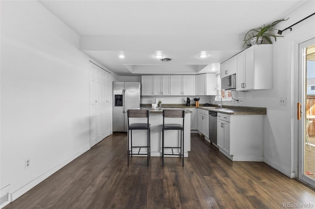 9044 E Nassau Ave, Denver, CO 80237 - kitchen featuring appliances with stainless steel finishes, dark wood-type flooring, a sink, a breakfast bar area, and recessed lighting