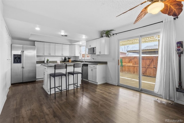 9044 E Nassau Ave, Denver, CO 80237 - kitchen featuring appliances with stainless steel finishes, dark countertops, a kitchen bar, white cabinets, and recessed lighting