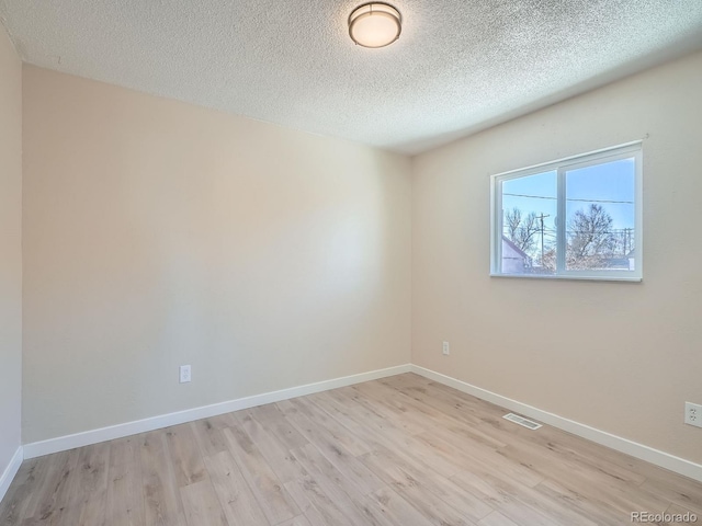 spare room with light wood-type flooring and a textured ceiling