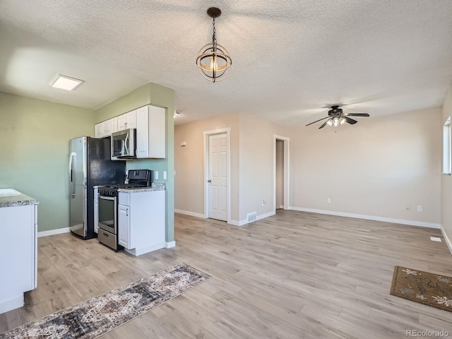 kitchen featuring a textured ceiling, decorative light fixtures, stainless steel appliances, white cabinetry, and ceiling fan with notable chandelier