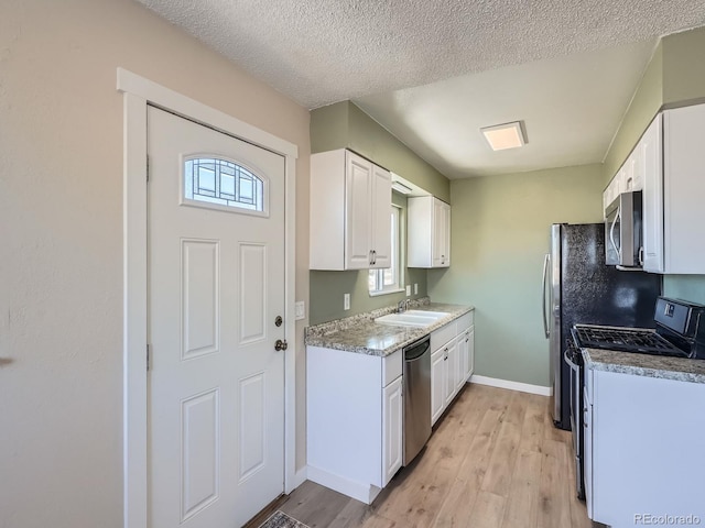 kitchen with sink, stainless steel appliances, white cabinetry, and a wealth of natural light