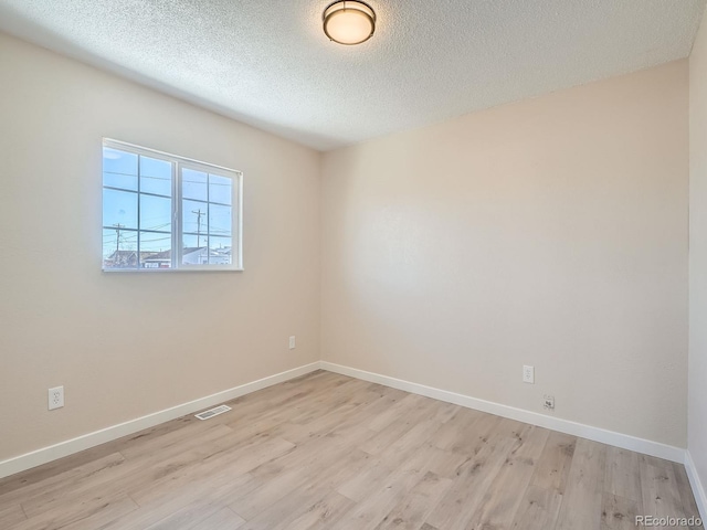 spare room with a textured ceiling and light wood-type flooring