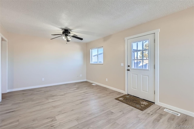 entryway with light wood-type flooring, ceiling fan, and a textured ceiling