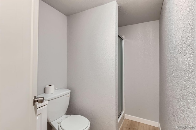 bathroom with toilet, wood-type flooring, and a textured ceiling