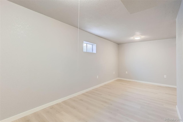 basement featuring light hardwood / wood-style floors and a textured ceiling