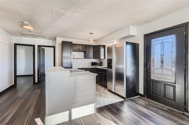 kitchen with stainless steel appliances, dark hardwood / wood-style flooring, pendant lighting, dark brown cabinets, and tasteful backsplash