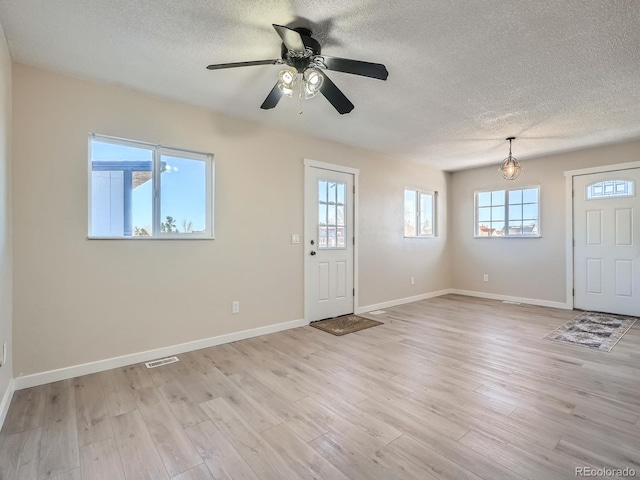 foyer entrance featuring a textured ceiling, ceiling fan, and light wood-type flooring