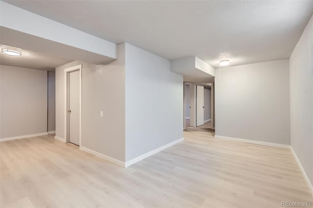 basement featuring light hardwood / wood-style floors and a textured ceiling