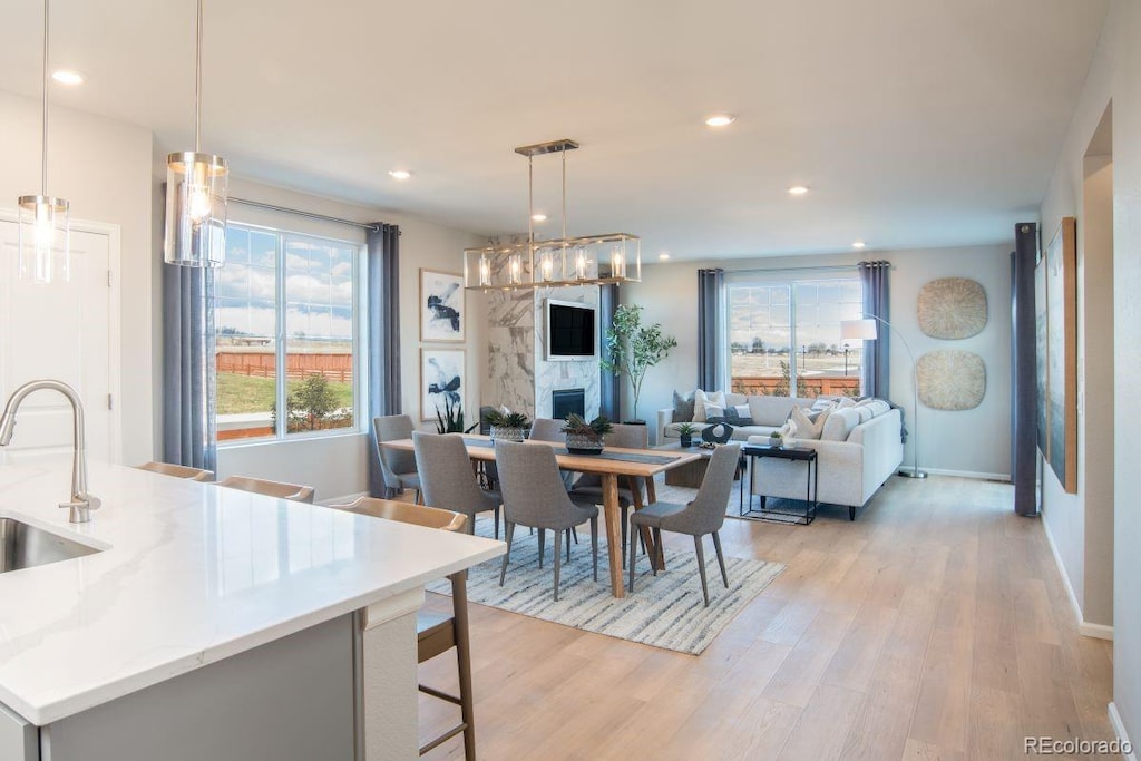 dining area with sink, a fireplace, and light hardwood / wood-style floors