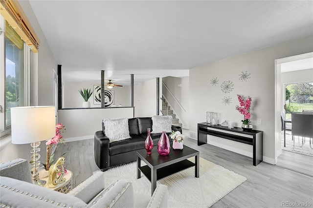 living area featuring stairs, wood finished floors, baseboards, and ceiling fan