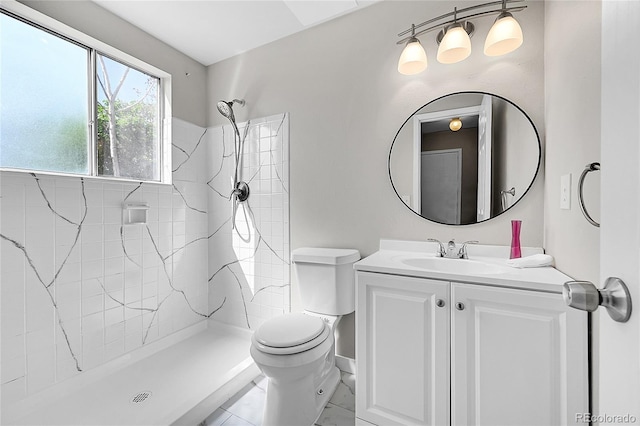 full bathroom with toilet, tiled shower, vanity, and baseboards