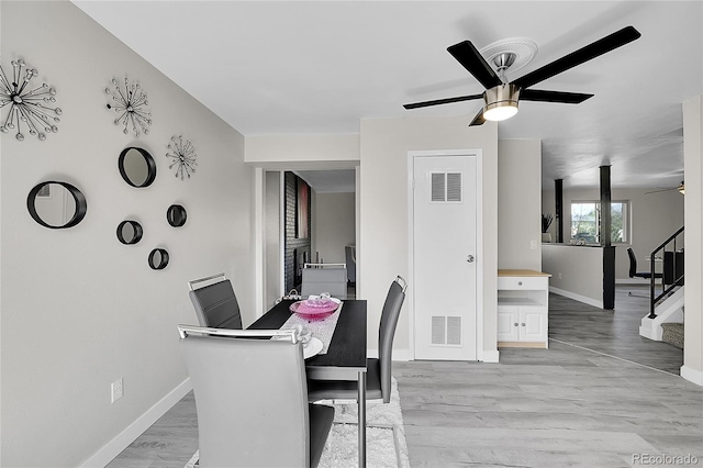 dining space featuring ceiling fan, baseboards, stairway, and light wood-style flooring