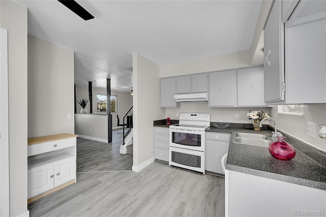 kitchen featuring range with two ovens, ceiling fan, dark countertops, a sink, and under cabinet range hood
