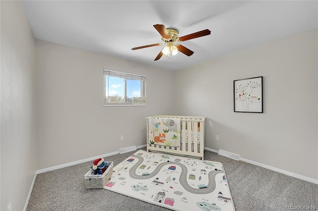 bedroom with carpet, baseboards, a nursery area, and ceiling fan
