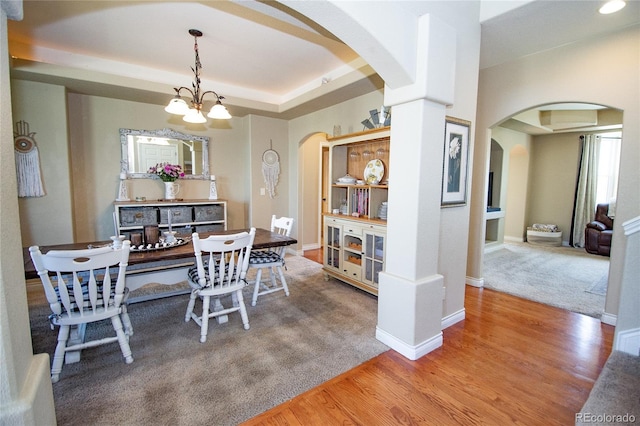 dining room with hardwood / wood-style flooring, a tray ceiling, and an inviting chandelier