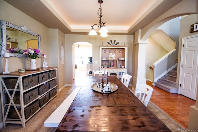 dining space featuring hardwood / wood-style flooring, a raised ceiling, and a chandelier