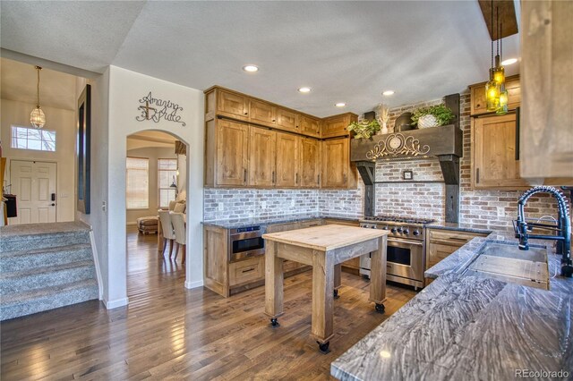 4142 S Deframe Ct, Morrison, CO 80465 - kitchen featuring high end stainless steel range, a sink, arched walkways, dark stone counters, and backsplash
